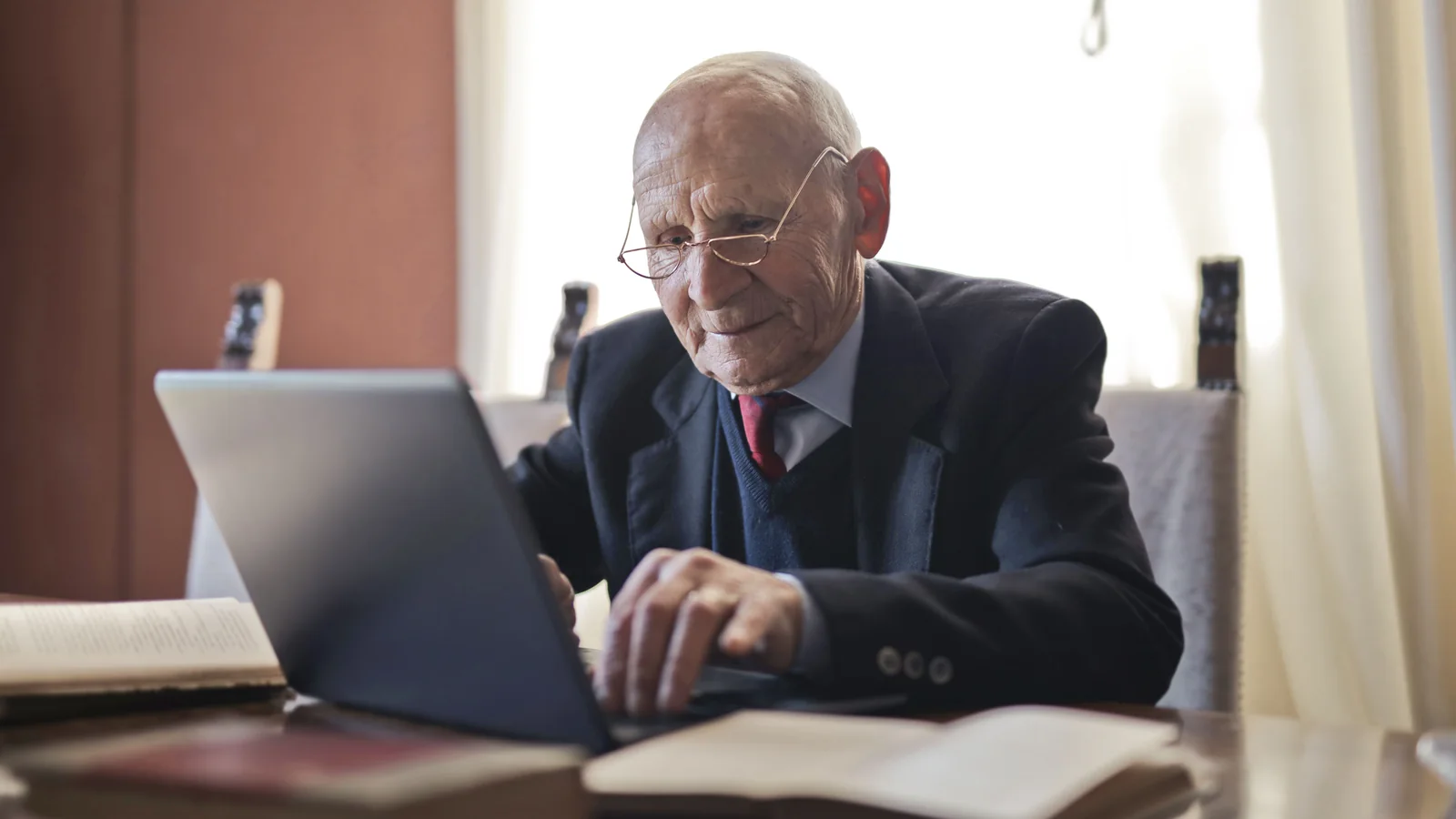 Un retraité consulte un ordinateur portable et des documents à son domicile