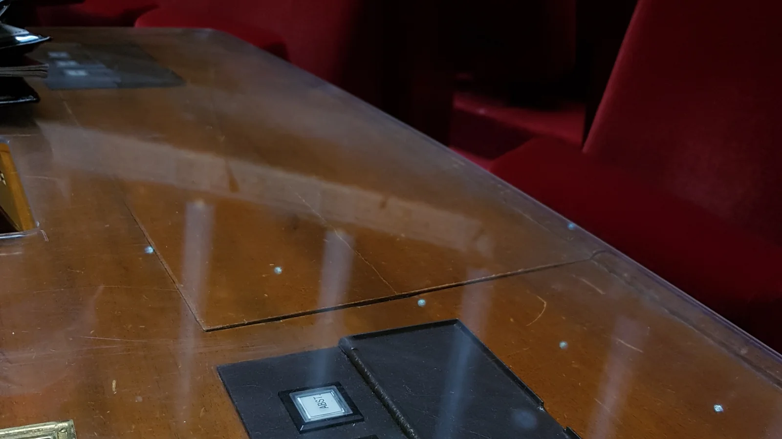 Boîtier d’abstention sur un pupitre face aux sièges rouges de l’Assemblée nationale