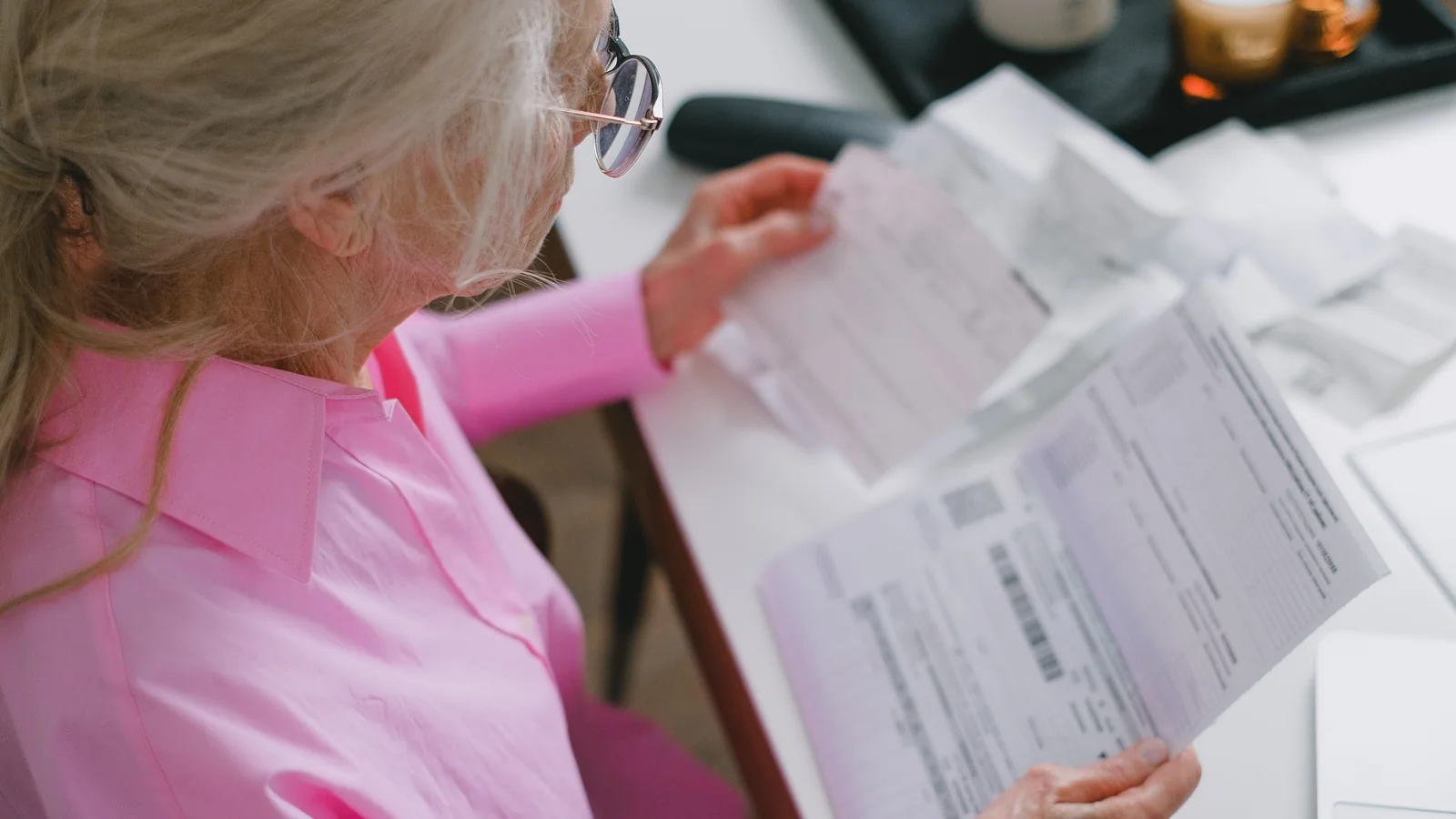 Une retraitée compare des documents de complémentaire santé à une table