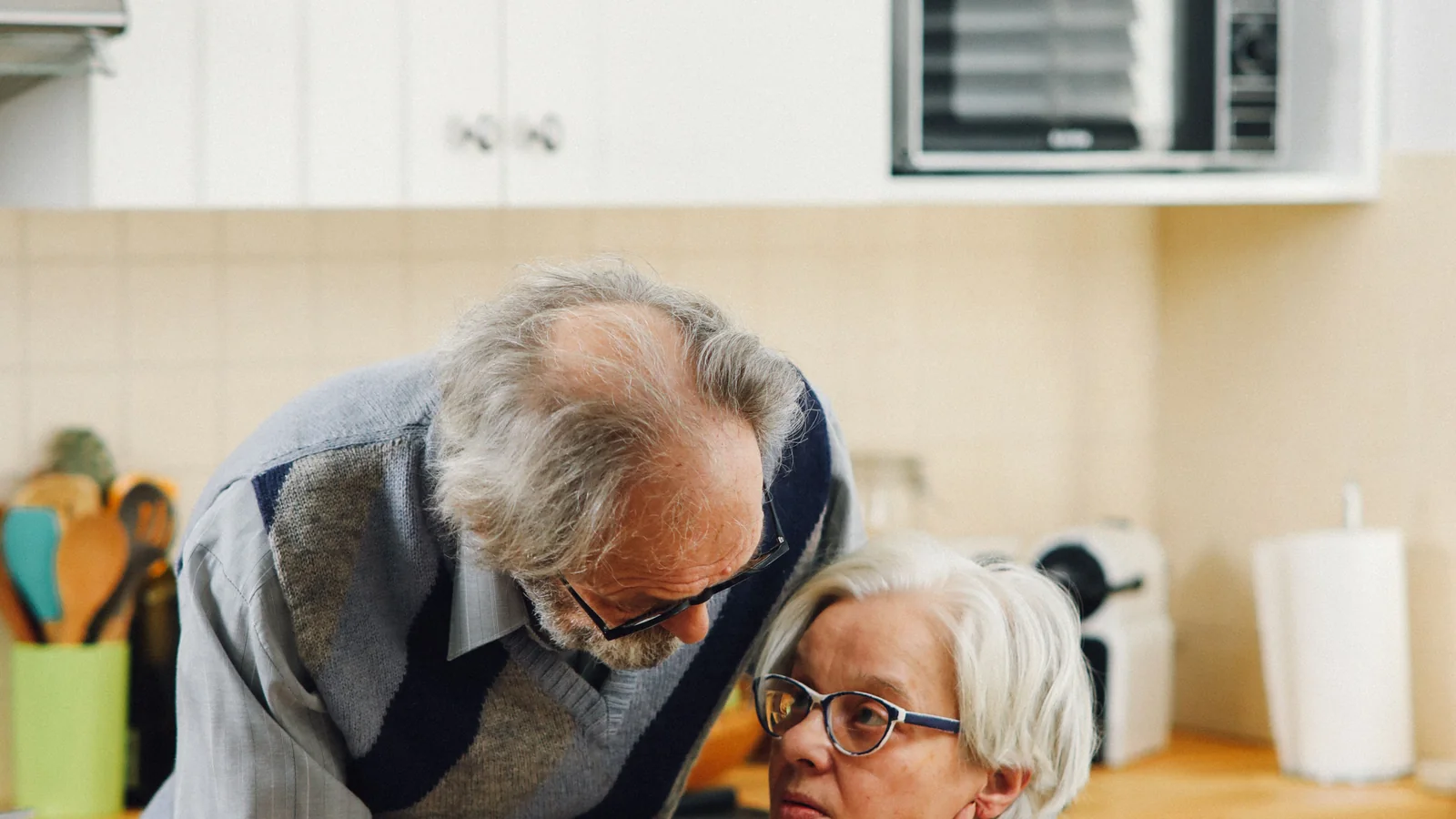 Un couple de retraités échange à la table de sa cuisine