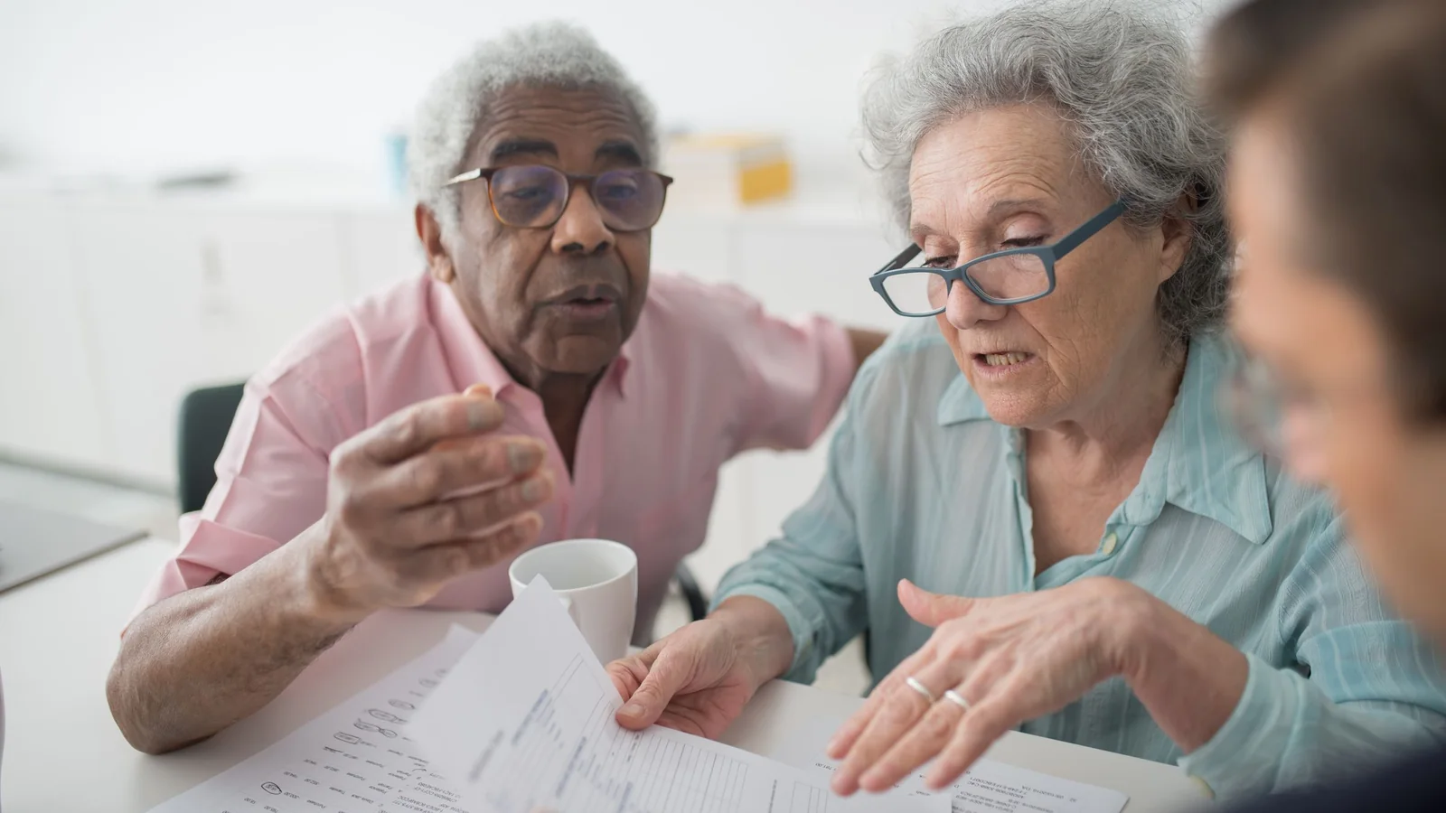 2 seniors examinent des documents avec un interlocuteur, illustration des choix liés à la retraite