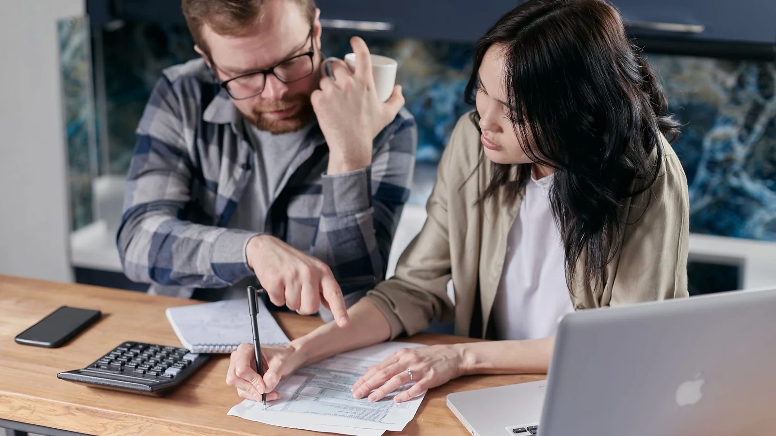 Un couple examine ses documents et son budget avec une calculatrice à la maison